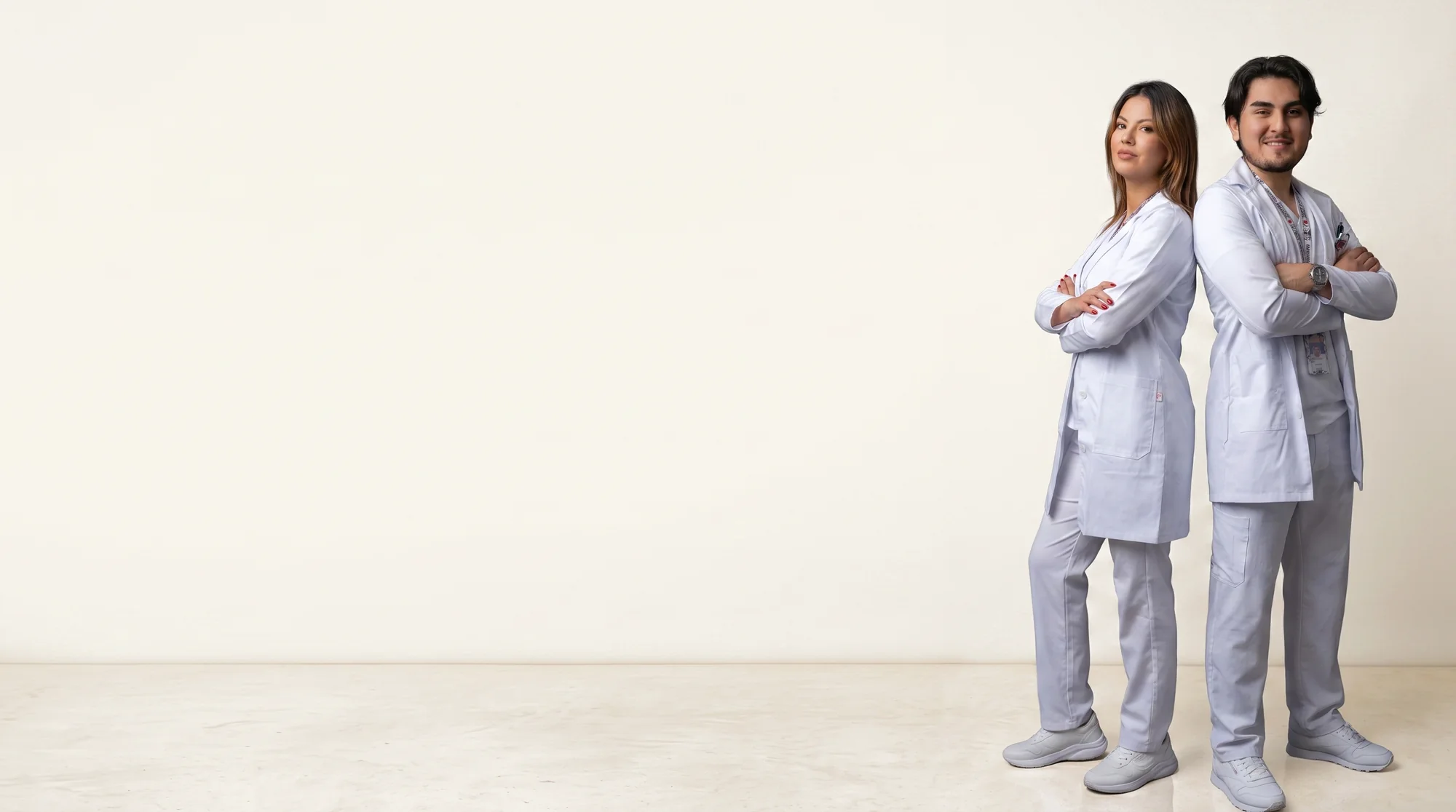 Dos profesionales de la salud de espalda con espalda, con bata blanca y uniforme clínico Unimagda